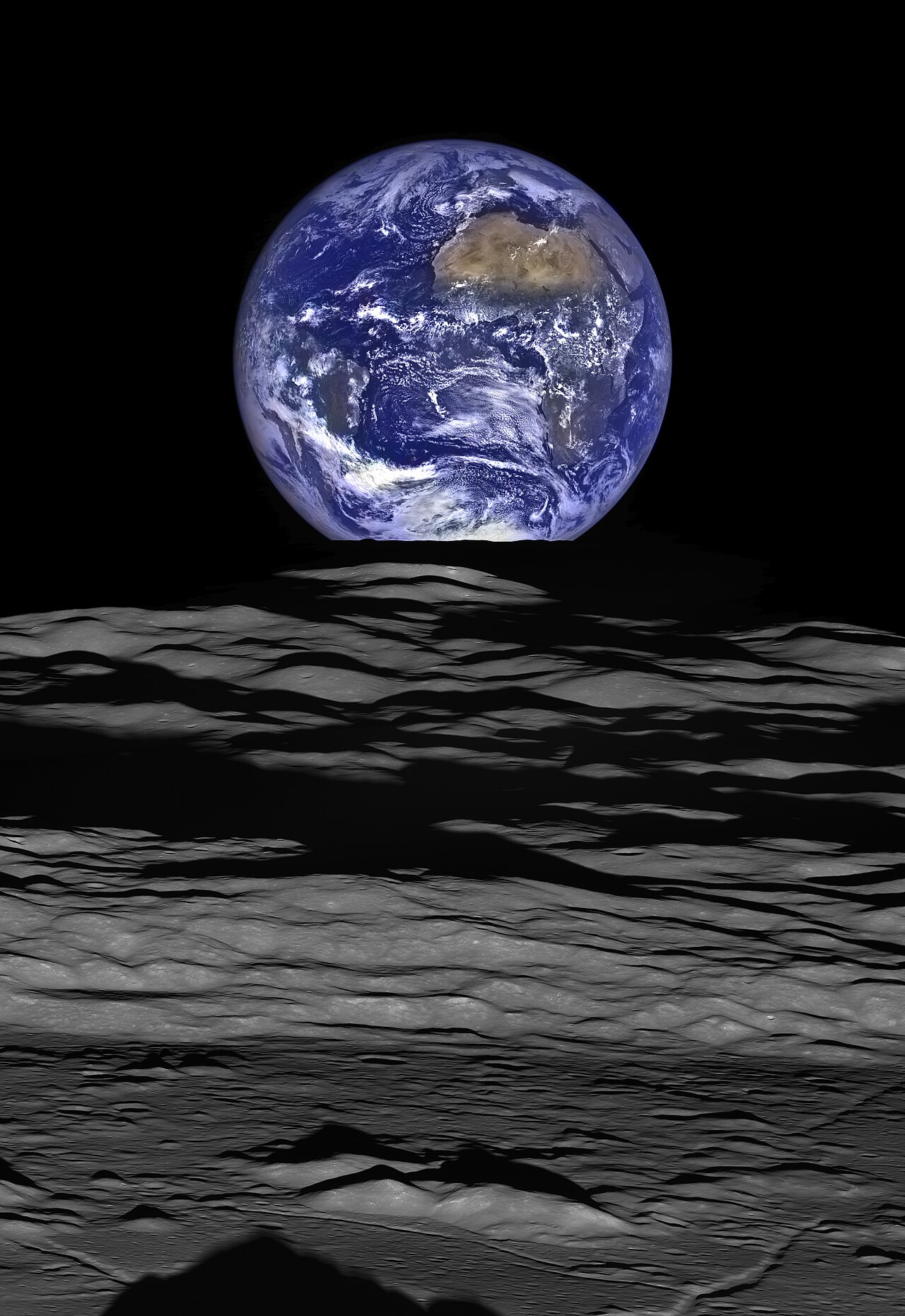 The Earth straddling the limb of the Moon, as seen from Lunar Reconnaissance Orbiter above Compton crater. The shadow in the foreground is from the crater's central peaks, while the mountains just abo