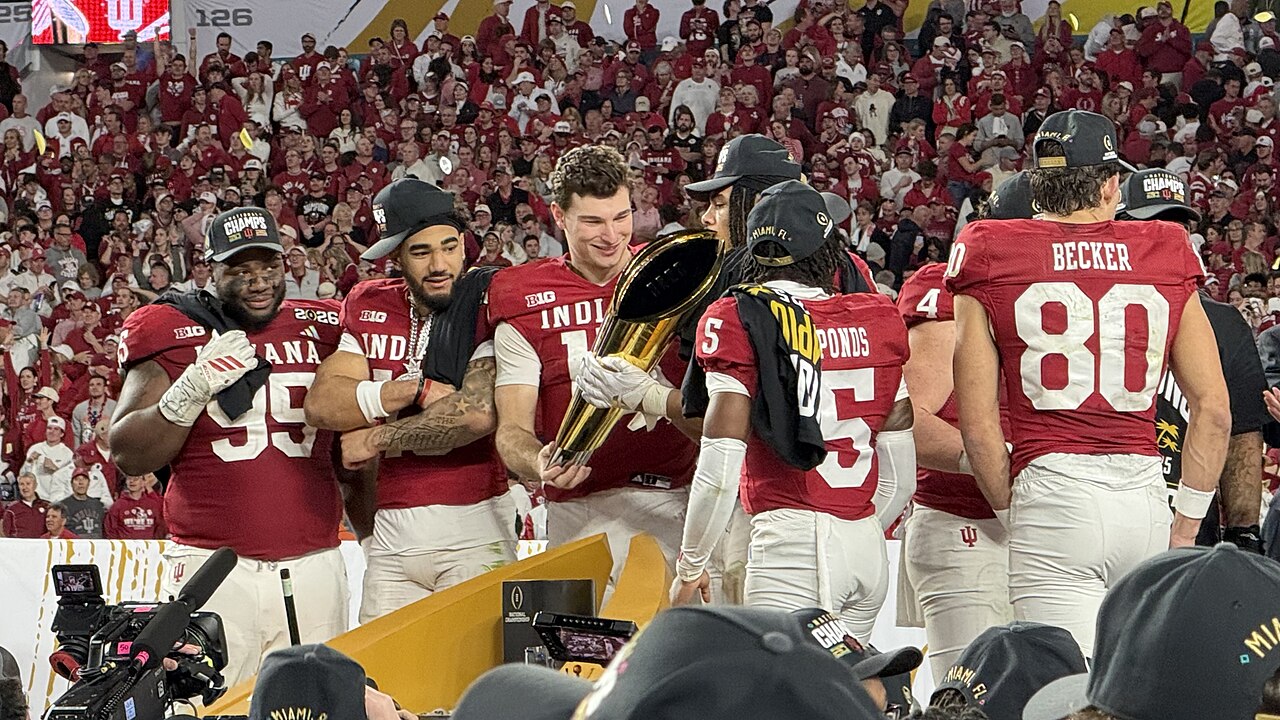 Members of the Indiana Hoosiers hold and admire the College Football Playoff National Championship Trophy after winning the 2026 CFP National Championship; the on the stage (placed on the field of Har